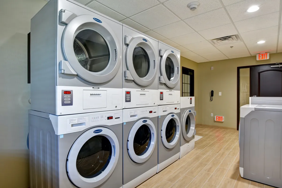 A practical laundry room featuring stacked washers and dryers against a clean wall. The space is bright and functional, emphasizing convenience and efficiency. The layout suggests self-serve accessibility, making it easy for guests to keep their wardrobe fresh during longer stays.