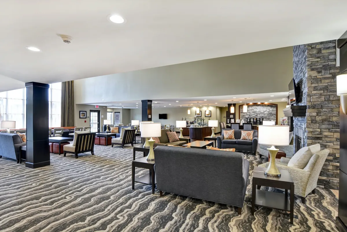 A cozy interior lounge centered around a stone fireplace, surrounded by comfortable seating and stylish decorative lamps. The ambiance is warm and inviting, ideal for socializing, reading, or unwinding in a relaxed atmosphere.